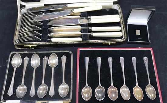 Two sets of six silver coffee spoons, 12 pairs of plated fish eaters and servers (all cased) and a silver facsimile stamp pin
